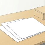 木の机の天板に、無地の紙が3枚少しずつずらして重ねて置かれている