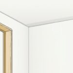 空室の中から天井と壁の取り合いを見上げた場面。左に明るい木の窓枠の縁