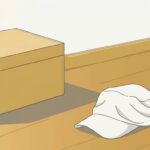 片付けが終わった明るい室内のすみ。ふたを閉じた明るい木の道具箱と、床に置かれた生成り色の布の作業帽。夕方の低い光が長い影を落としている