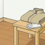 冬の朝の空室のすみ。木の踏み台の上に、たたんだ作業用の厚手の上着と布の作業手袋が置かれている